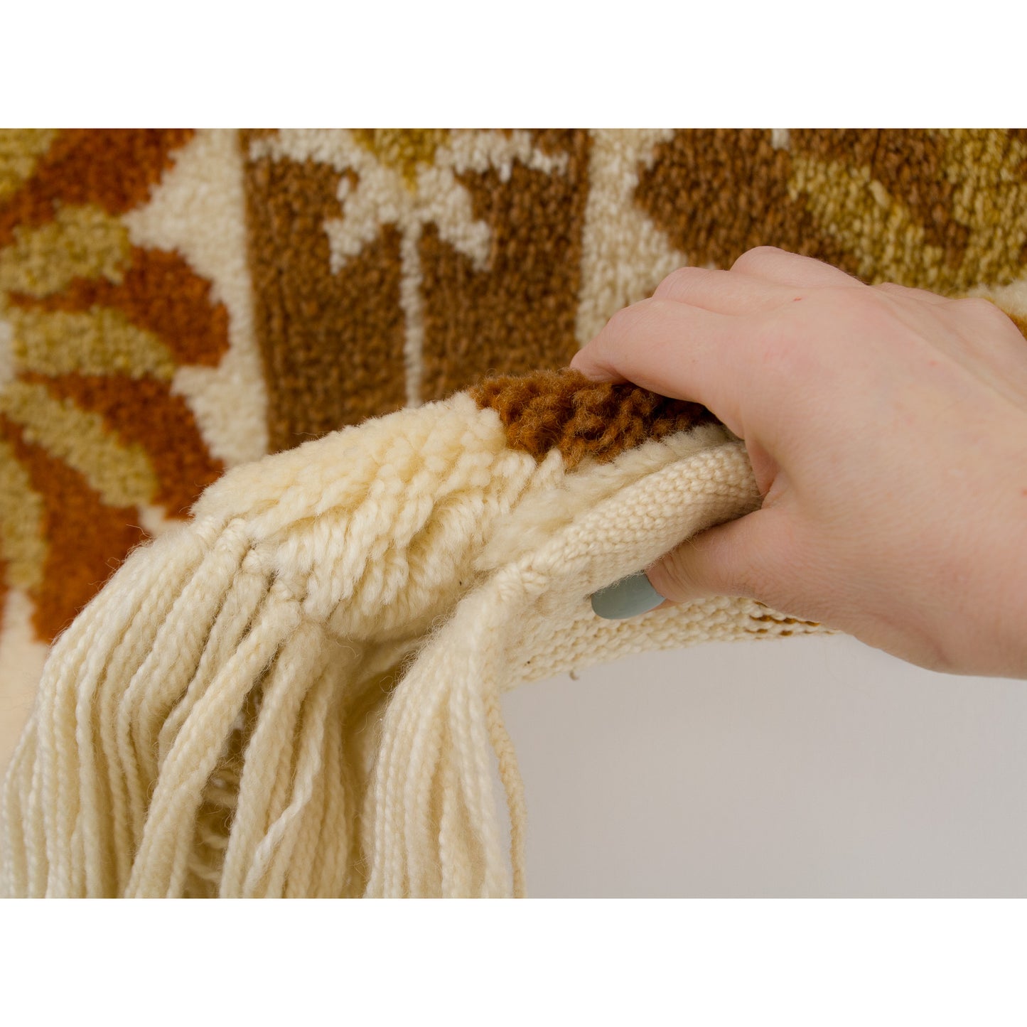 Hand gently draping the soft wool surface of the tapestry, highlighting the plush, carpet-like feel of this heavyweight wall decor.