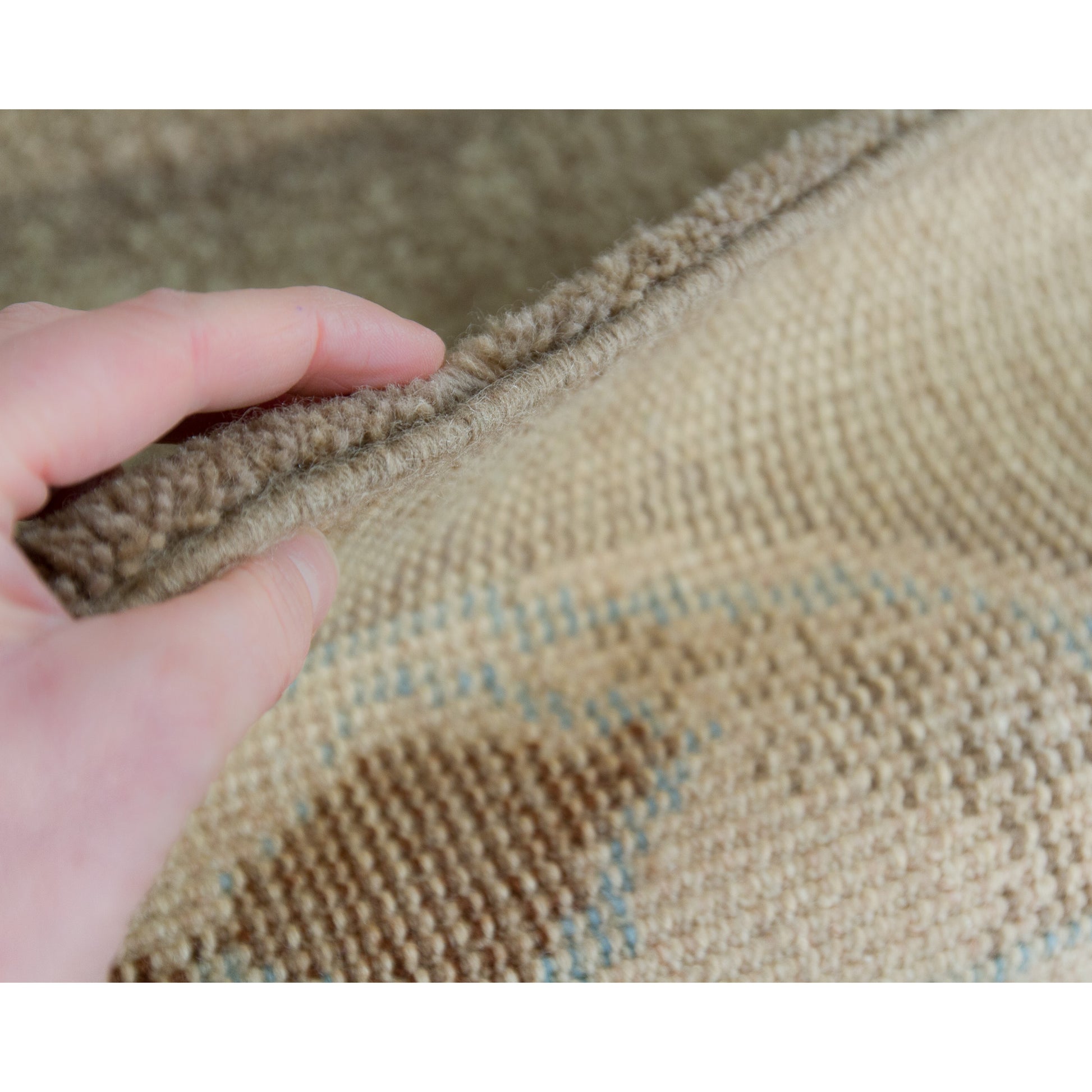 Hand holding the sturdy edge of the wall tapestry, displaying its substantial 16-pound thickness. Heavy enough for the floor, yet stunning enough to command a wall.