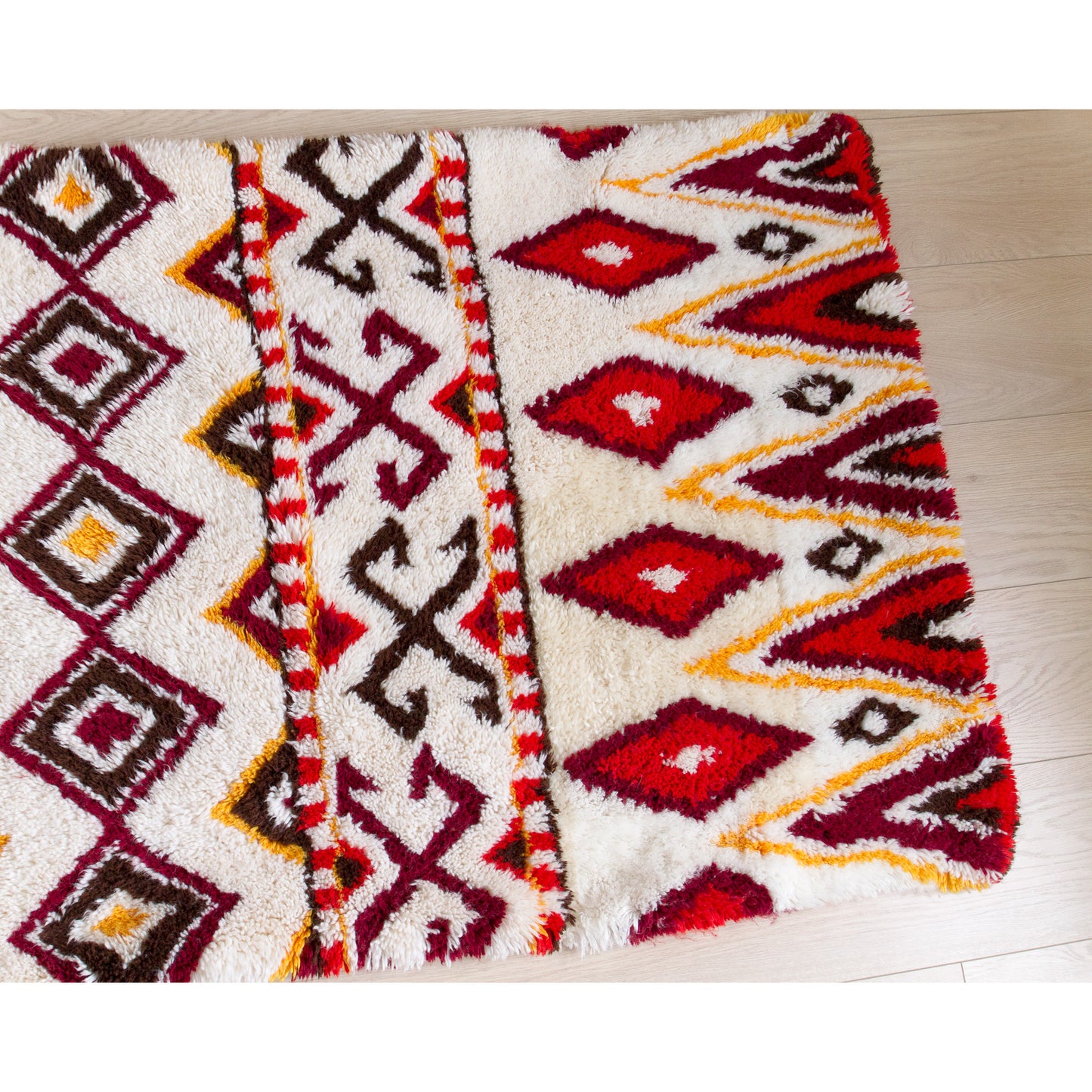 Right half of the 1970s handmade shag tapestry, highlighting the perfect symmetry of the tribal-inspired retro triangle and diamond designs.