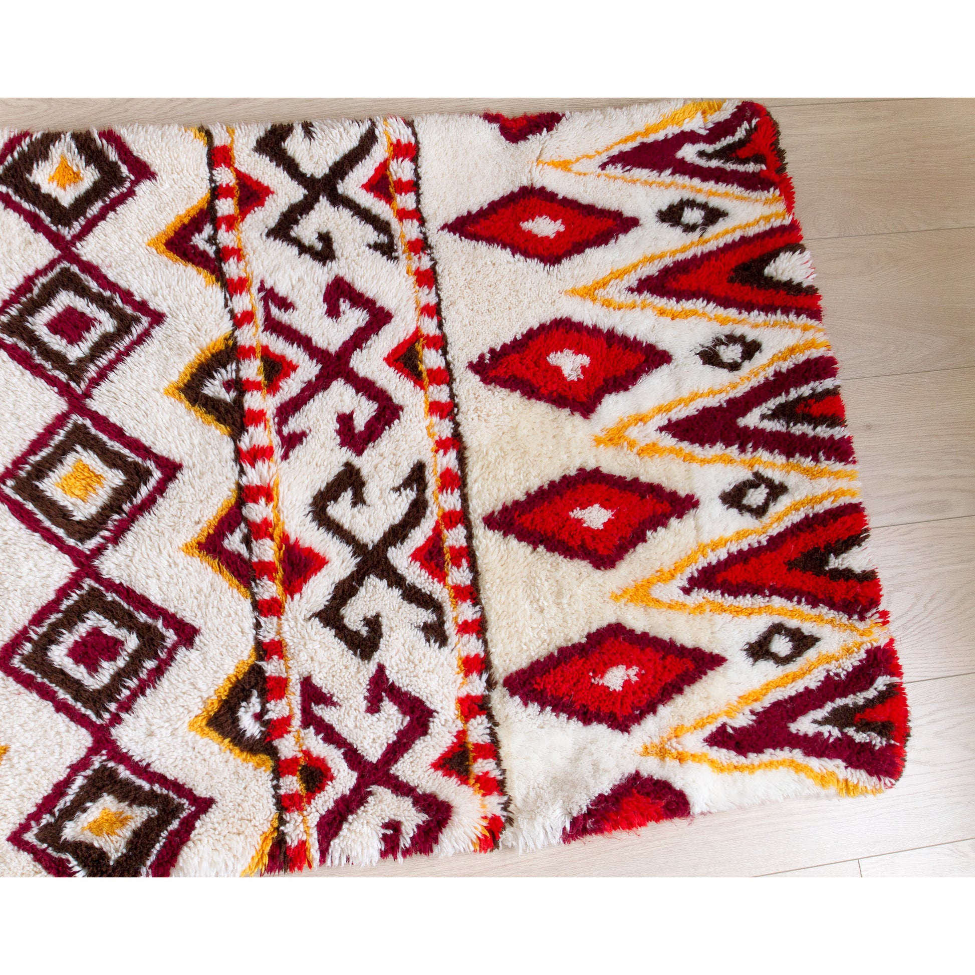 Right half of the 1970s handmade shag tapestry, highlighting the perfect symmetry of the tribal-inspired retro triangle and diamond designs.