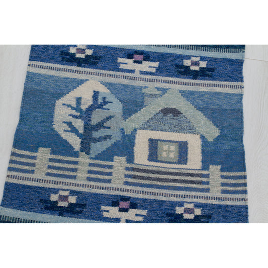 Detail of the "Sweet Home" motif: A small white house with a blue roof, a tree, and a picket fence woven in wool.