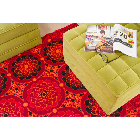 Top view of a lime green tufted ottoman in a retro 70s living room setting, styled with  a bold red and orange Flower Power vintage rug, creating an authentic 1970s "Mad Men" interior.