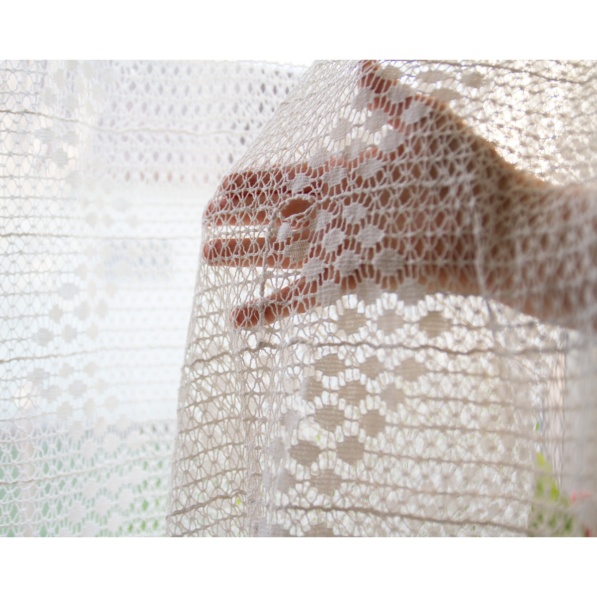 Close-up of vintage crochet lace over a hand, showing the small flower motifs and fine thread