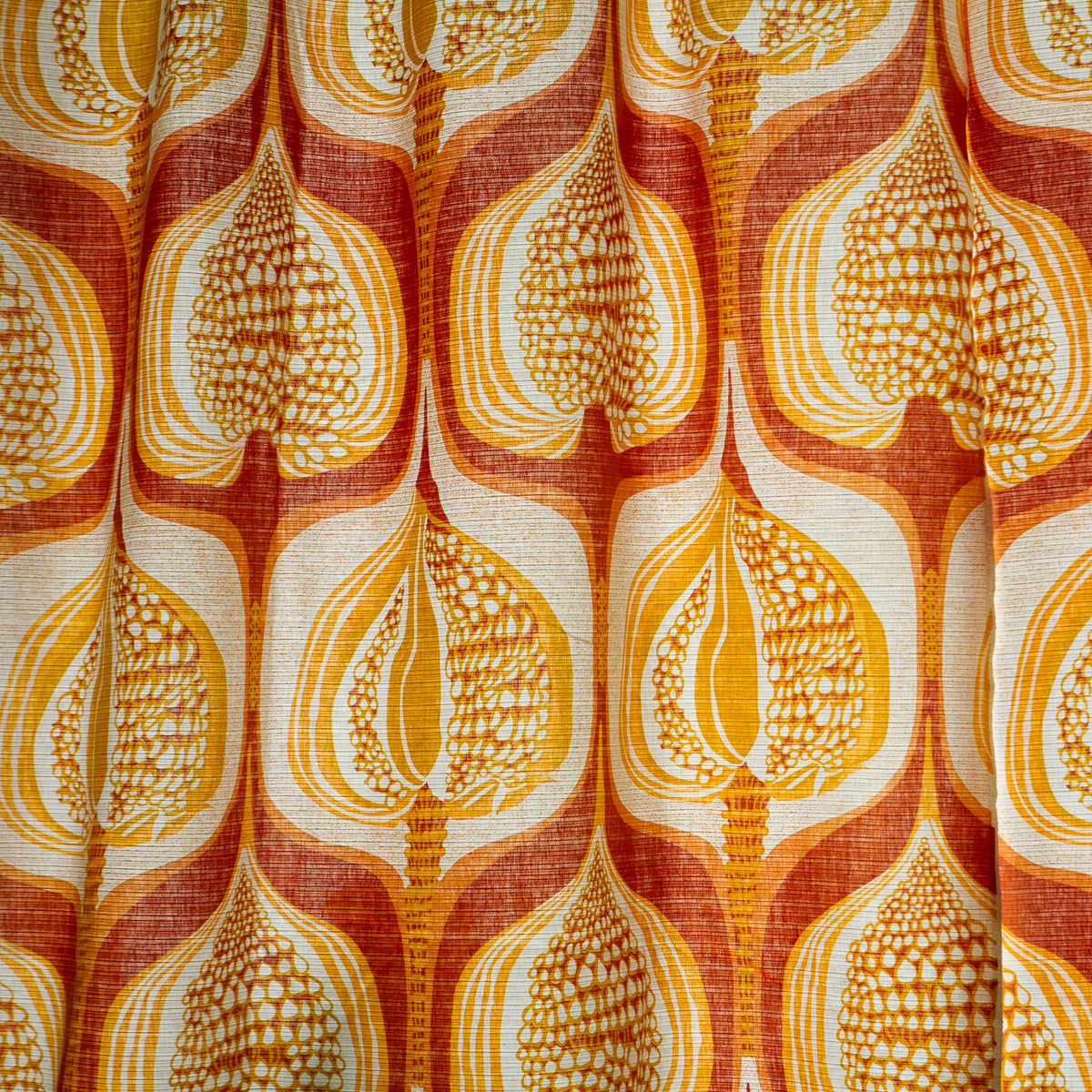 Close-up of vintage curtain pattern with organic, stylized seed pods or autumn leaves in orange, mustard and cream