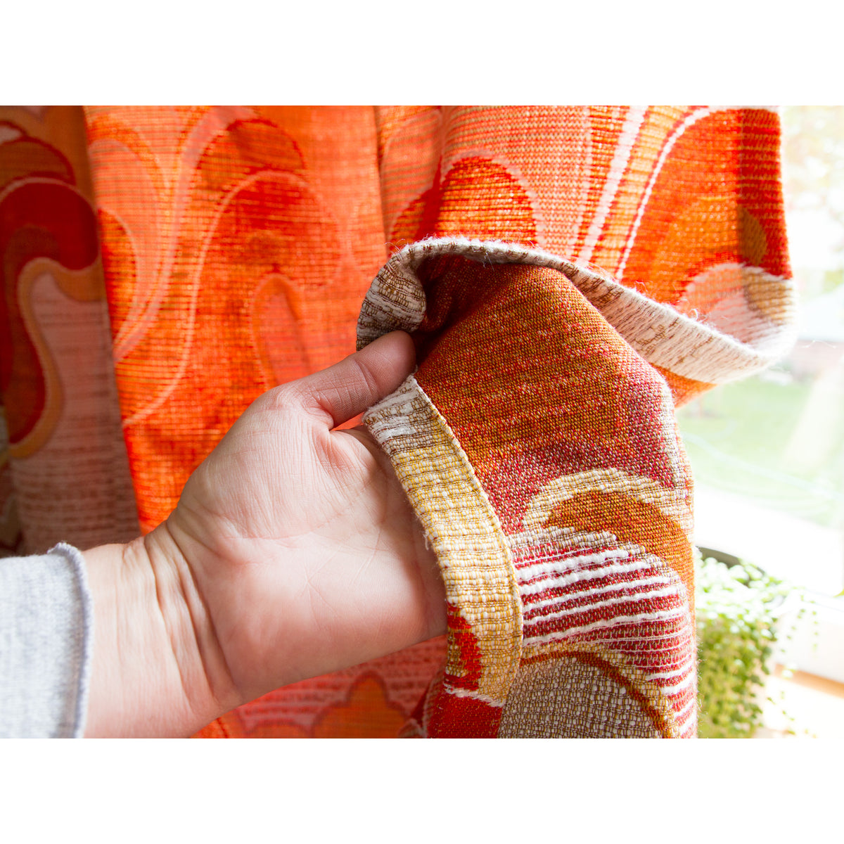 Hand folding vintage drape to show the reverse side and neat hem, the pattern woven into the fabric not printed