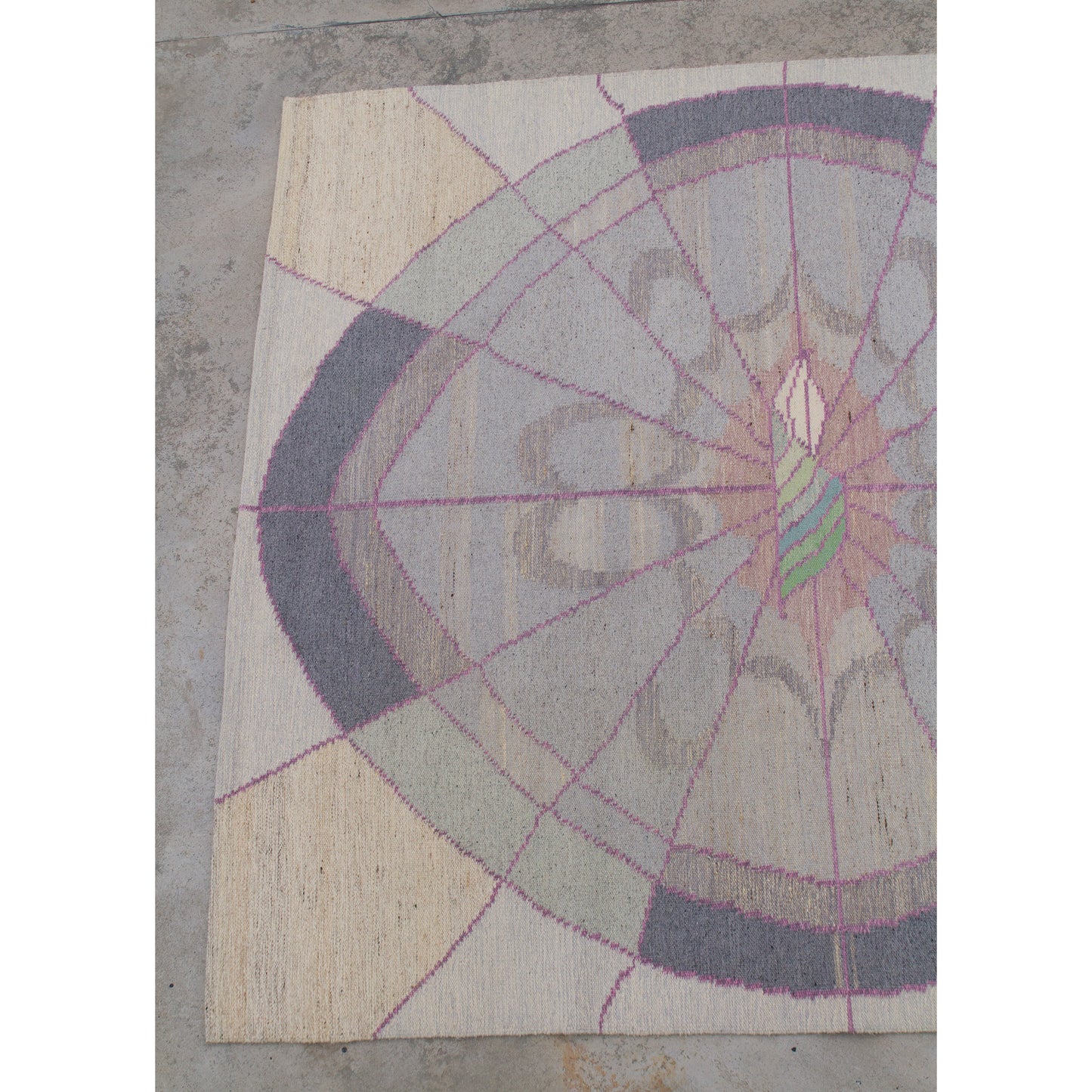 Left segment of a large nearly square vintage flatweave wool rug. Pastel dusty pink, grey, and cream with an abstract 80s geometric sunburst motif.
