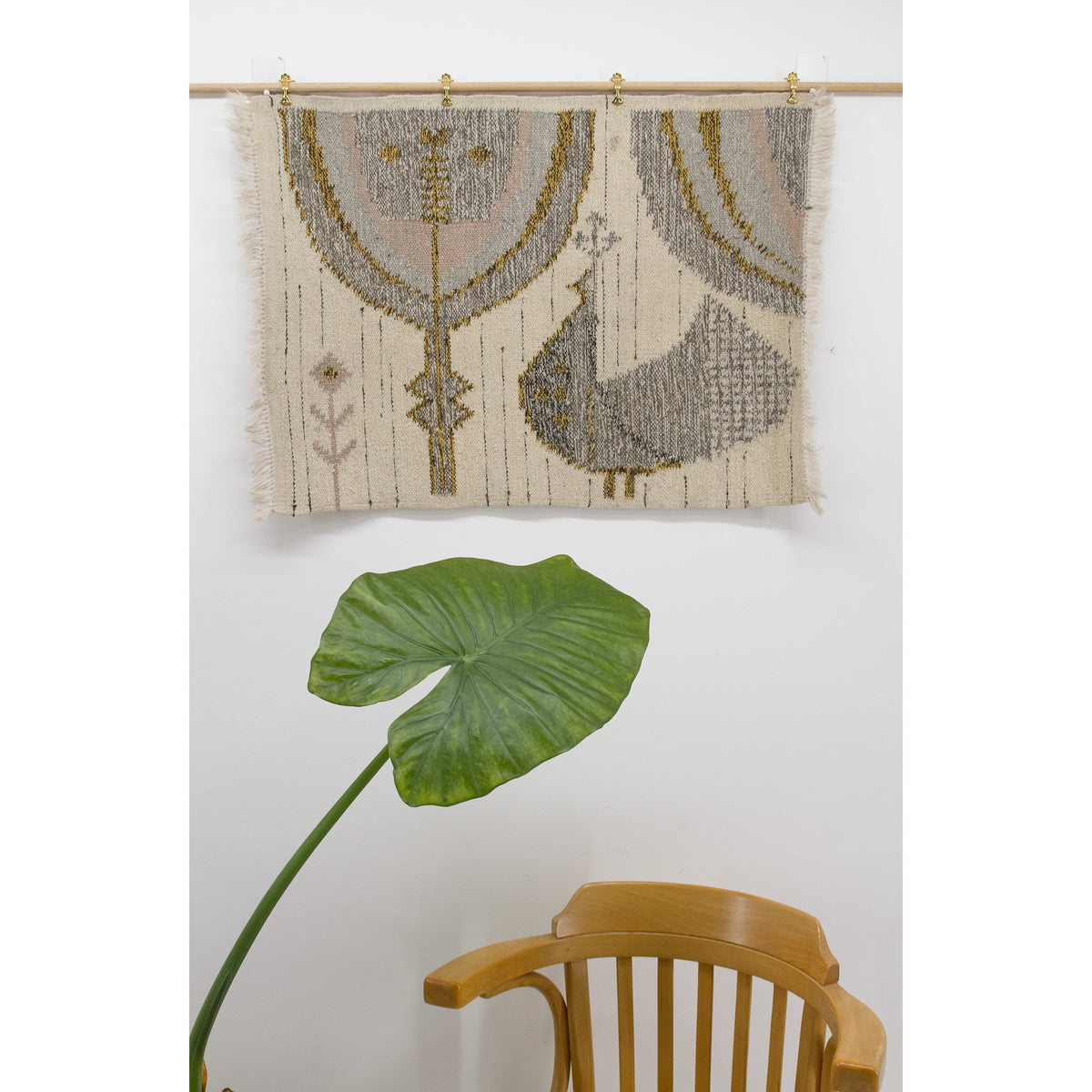 Styled shot of the small vintage rug displayed on a white wall, providing an easy to follow method for hanging a vintage tapestry by using curtain clips and a dovel.