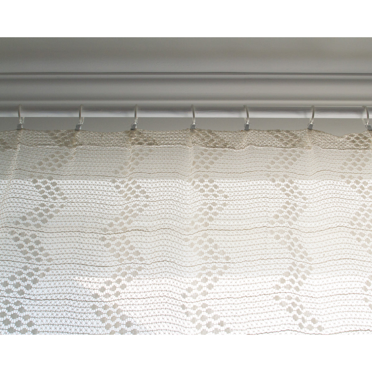 Wide view of vintage lace panel hanging from curtain clips, showing the zigzag lace pattern