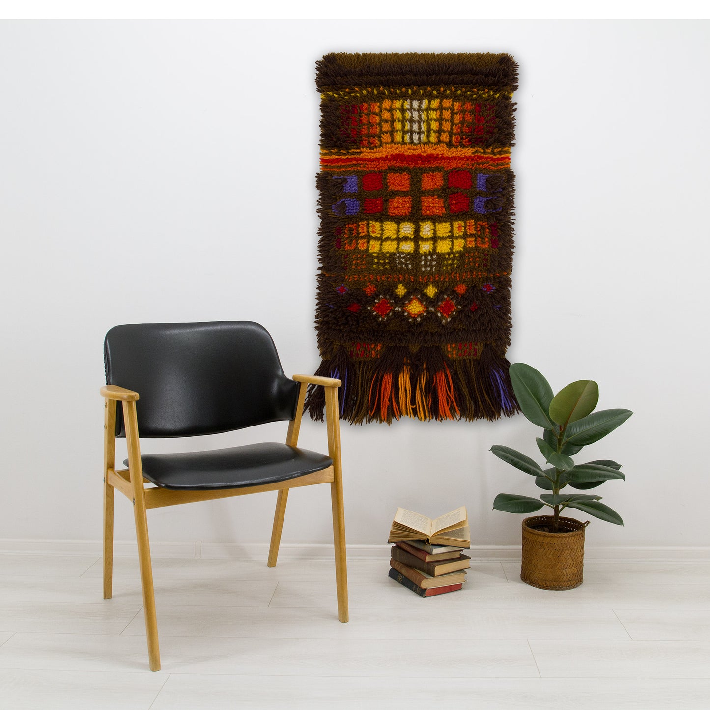 Mid-century modernist room decor showing a West German space age rya wall hanging displayed perfectly over a sleek black leather chair.