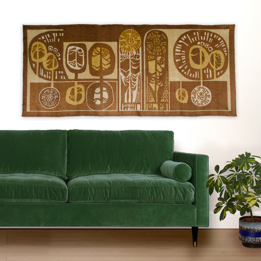 Styled living room with an oversized tapestry displayed above the mid century modern sofa. The large vintage textile art acts as a statement piece wall decor, with its warm chocolate brown, caramel and beige colors and organic abstract design that resembles of trees / forest.