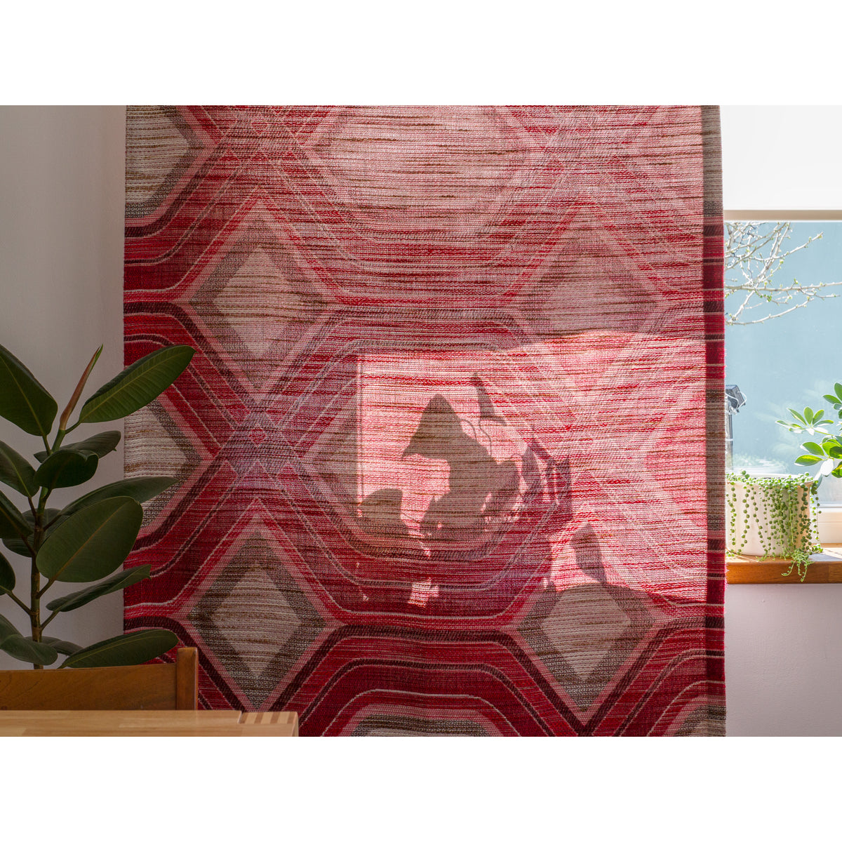 Vintage red geometric curtain panel hanging by a window, demonstrating light-filtering and translucent qualities of the fabric.