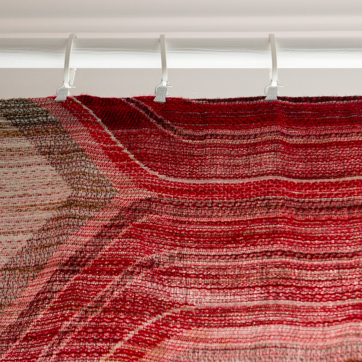Top of vintage red curtain panel hung with curtain clips on a rod