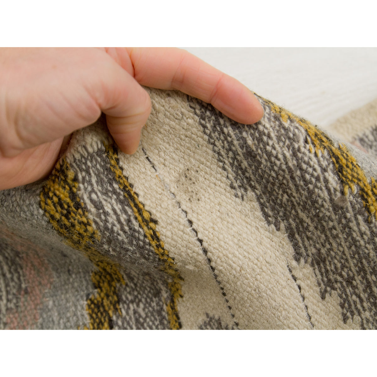 Macro shot of the cream wool background near the center seam. The photo clearly shows a small, faint greyish age spot or shadow, providing transparent documentation of the authentic vintage condition and patina of the piece.