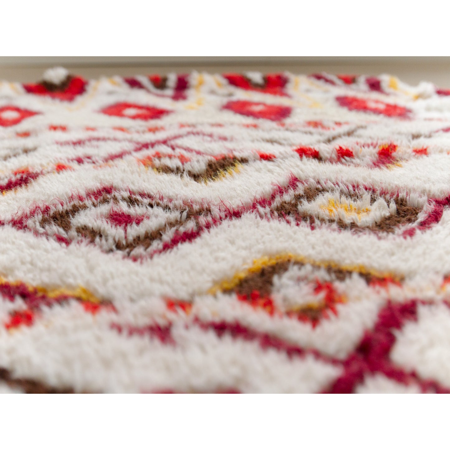 Extreme low-angle 'bug's eye' view deep into the thick, luscious shag fibers of the handmade rug. Demonstrating that the white fibers are completely unstained and vivid.