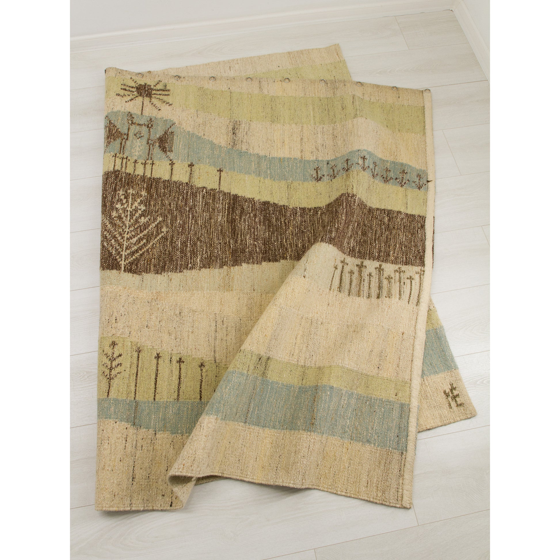 The large tapestry folded over on the floor, highlighting the dense, soft woven wool weft on strong cotton warp. Quality to last.