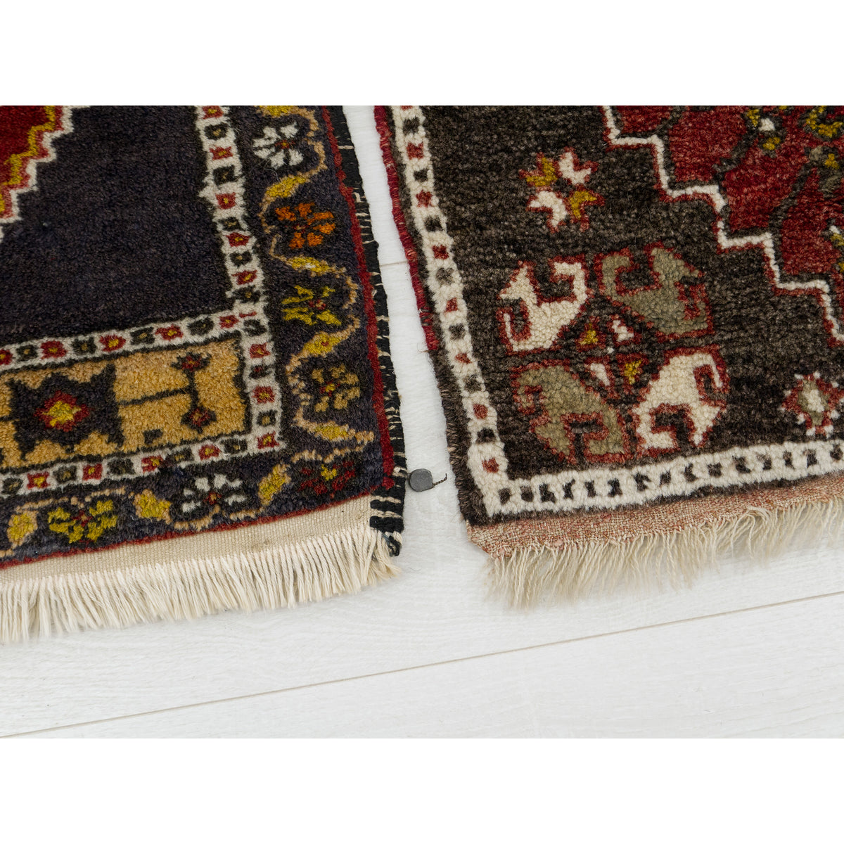 Ends of two vintage Turkish rugs side by side, showing the wool fringe and colorful borders