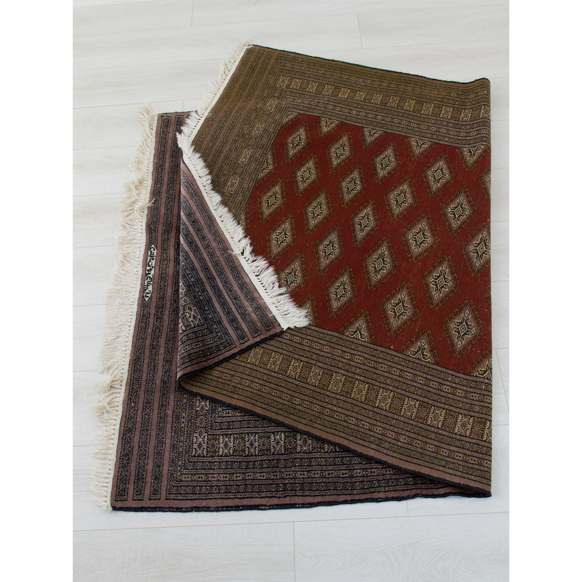 Vintage Turkoman style rug folded to show the reverse side and excellent, perfect condition
