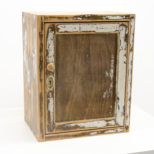 Small vintage wall cabinet, refurbished and ready to use: a rustic wooden cabinet with a distressed finish, featuring peeling white paint on a brown wood base, a round wooden knob, and a brass keyhole, set against a plain white background.