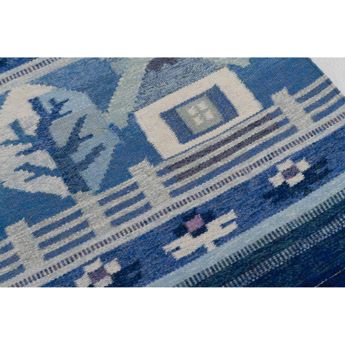 Detail of the "Sweet Home" motif: A small white house with a blue roof, a tree, and a picket fence woven in wool. Shades of navy, sky blue, and cream create a serene, calm night color palette.
