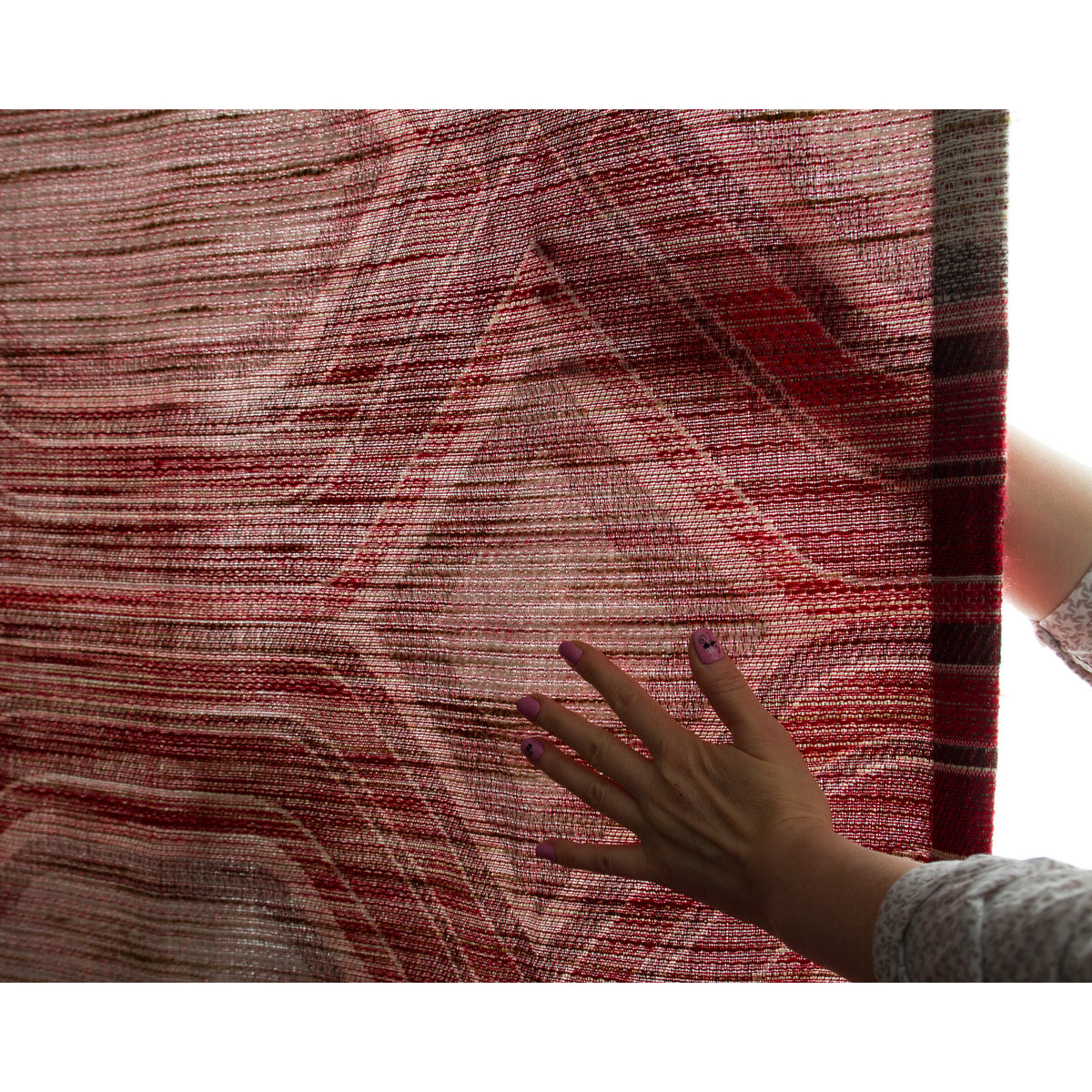 Hand behind backlit vintage light filtering curtain showing texture and warm red glow