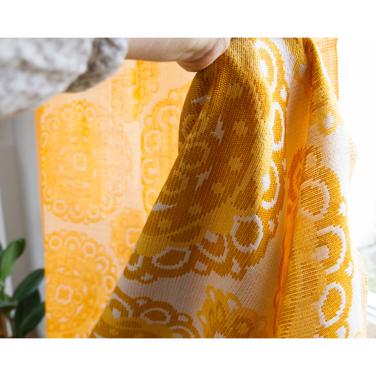 Close-up of 1970s jacquard curtain fabric with woven medallion pattern in golden yellow, mustard and cream colors.
