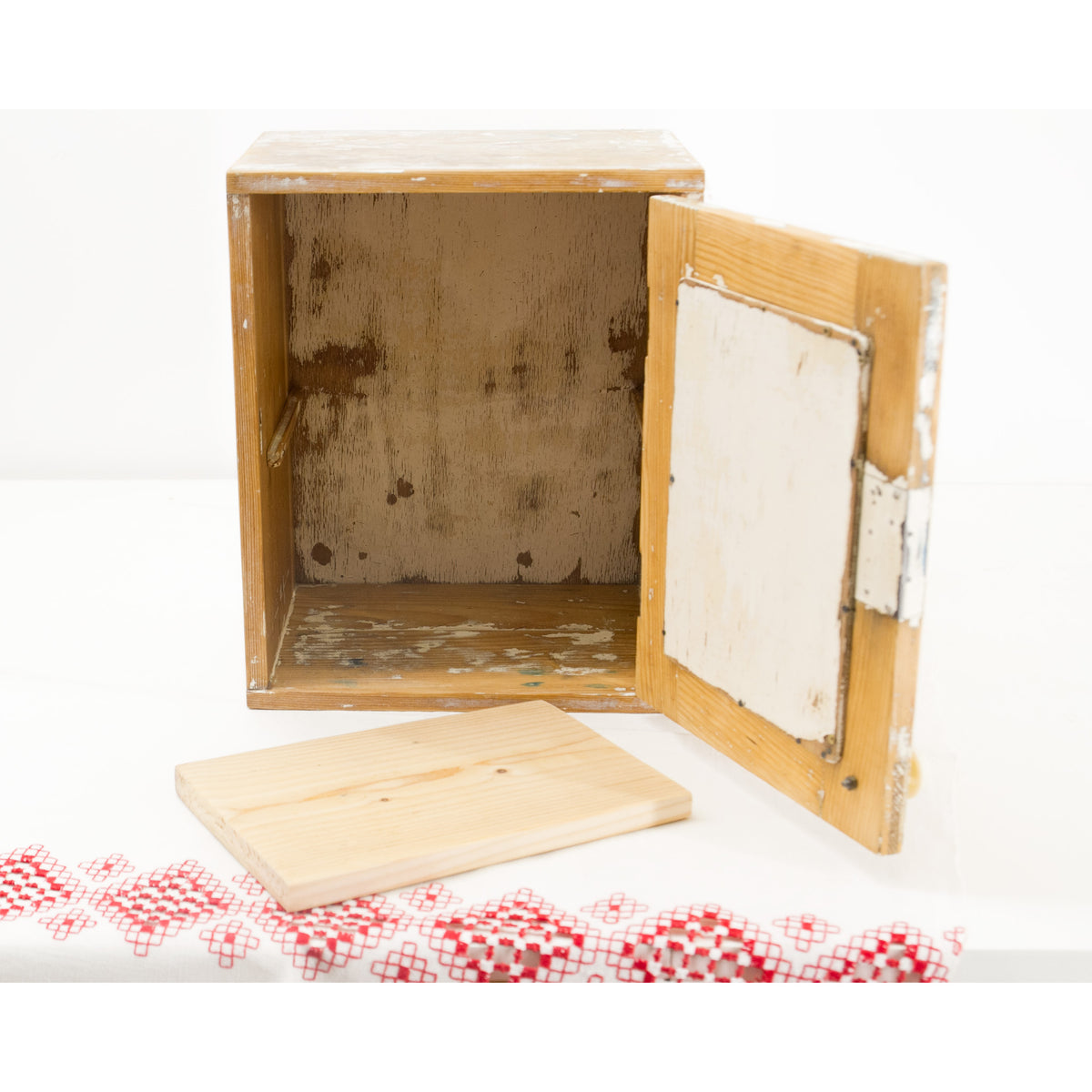 A small, rustic bathroom wall cabinet with a weathered, peeling paint finish, shown open with its removable shelf placed in front on a white surface. The petite size makes this furniture perfect for a small farmhouse bathroom or rustic style entryway.